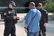 Strażnicy miejscy z oddziału specjalistycznego legitymują mężczyznę w dżinsowej koszuli.