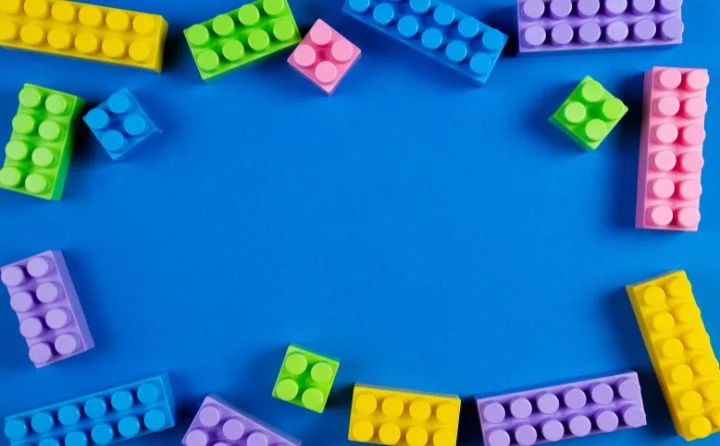 kolorowe klocki LEGO rozrzucone na niebieskim tle