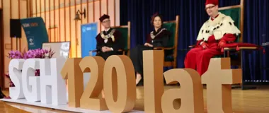 Uroczystość jubileuszowa SGH z okazji 120-lecia uczelni, podczas której na scenie zasiadają osoby w togach i insygniach władz akademickich.