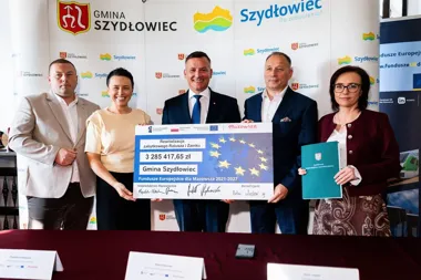 Przedstawiciele Gminy Szydłowiec i władz województwa mazowieckiego pozują z symbolicznym czekiem na rewitalizację zabytkowego ratusza i zamku podczas uroczystoś