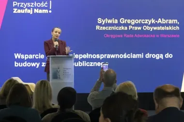 Kobieta przemawia z mównicy podczas konferencji zorganizowanej przez Okręgową Radę Adwokacką w Warszawie, na tle ekranu z hasłem „Przyszłość Zaufaj Nam”.