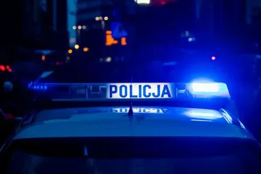Policyjny radiowóz z włączonym niebieskim światłem na ulicy nocą.