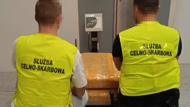 Funkcjonariusze Służby Celno-Skarbowej stoją przy wadze z zapakowanym towarem.