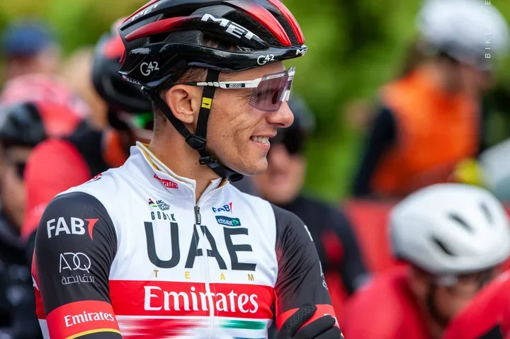 Kolarz w barwach UAE Team Emirates stoi w grupie przed lub po wyścigu kolarskim.